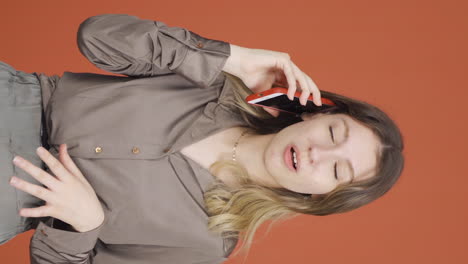 Vertical-video-of-Happy-talking-young-woman-on-the-phone.